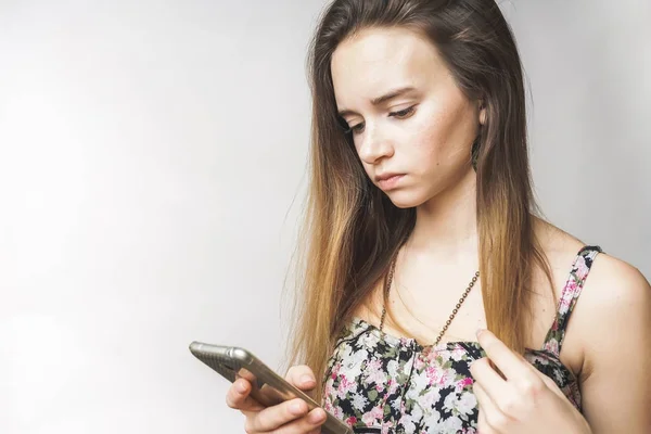 Donna in cerca di qualcosa in smartphone, depresso, su uno sfondo bianco — Foto Stock