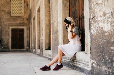 Bir cami eşiğinde bir eşarp genç bir kadın oturur