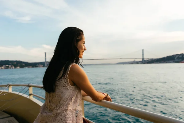 Счастливый пассажир круизного судна снаружи на балконе люкса, наслаждаясь роскошным видом на океан и мост в туристическом направлении летом. Латинская женщина . — стоковое фото