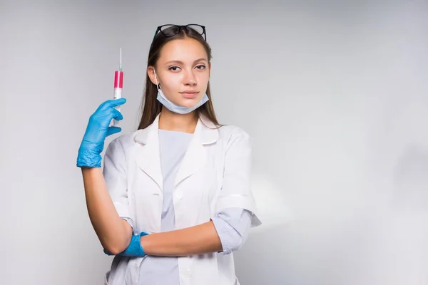 Ung självsäker tjej läkare i vit medicinsk morgonrock innehar en spruta i handen — Stockfoto