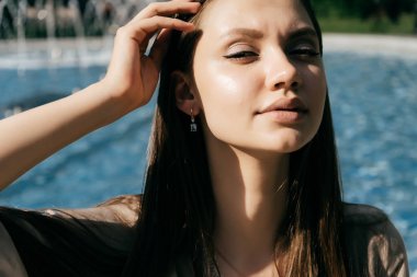 güneşin altında poz ile mavi su, havuz çekici güzel kız oturuyor