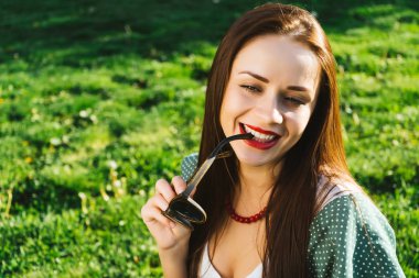 Gülümseyen kadın güneş gözlüğü, boşaltmak tutar. Gözlük ile her yerde yeşil çimen