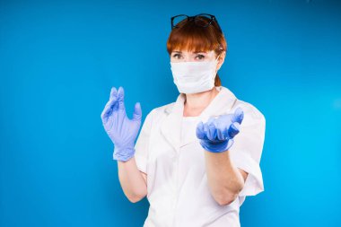 Yetişkin Kızıl saçlı kadın doktor beyaz koruyucu tıbbi maske ve laboratuvar kat poz