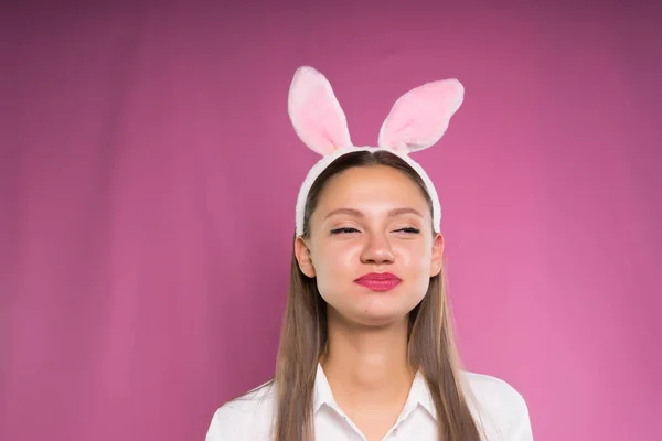Een grappig meisje in een wit overhemd, met een rand in de vorm van de oren van het konijn op haar hoofd, lacht — Stockfoto