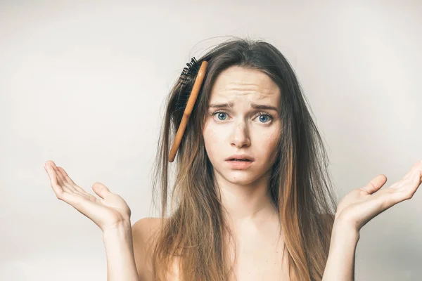 Cabelo pente nos cabelos, problemas, mulher questionando, parece triste, em um fundo branco — Fotografia de Stock