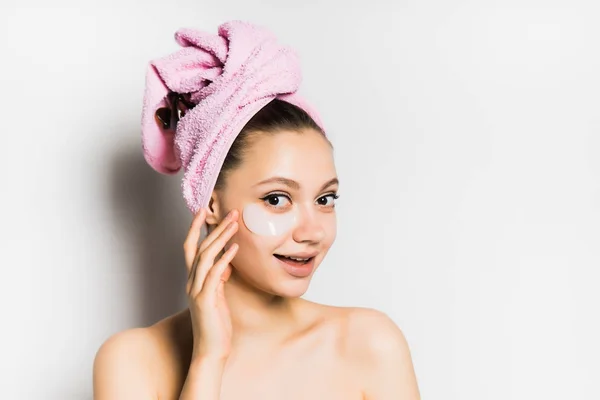 Niña feliz con la piel limpia, toalla rosa en la cabeza, parches de silicona bajo los ojos mirando a la cámara, sonriendo — Foto de Stock