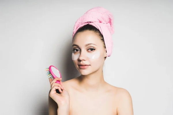 Joven sorprendida con la piel limpia, toalla rosa en la cabeza, parches de silicona bajo los ojos mirando a la cámara, sonriendo — Foto de Stock