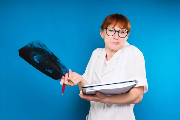 Felnőtt, vörös hajú nő orvos visel szemüveget tart egy x-ray fogak és egy notebook, nem tudom, mit tegyek — Stock Fotó