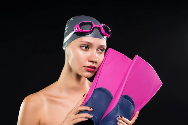 Confident athletic young girl swimmer in a swimming cap and glasses holds bright fins — Stock Photo, Image