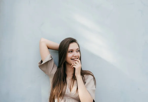 Attraktiva sexig tjej poserar vid en ljus vägg, leende och ser glad — Stockfoto