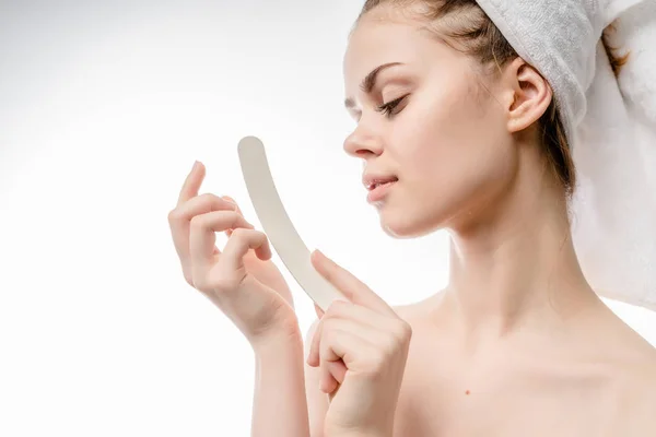 Mooi meisje met een witte handdoek op haar hoofd zagen haar vingernagel nagelvijl — Stockfoto