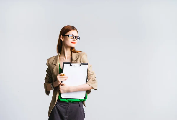 Stilvolles nachdenkliches Mädchen mit Brille, mit rotem Lippenstift hält einen Ordner mit Dokumenten in der Hand, schaut zur Seite — Stockfoto
