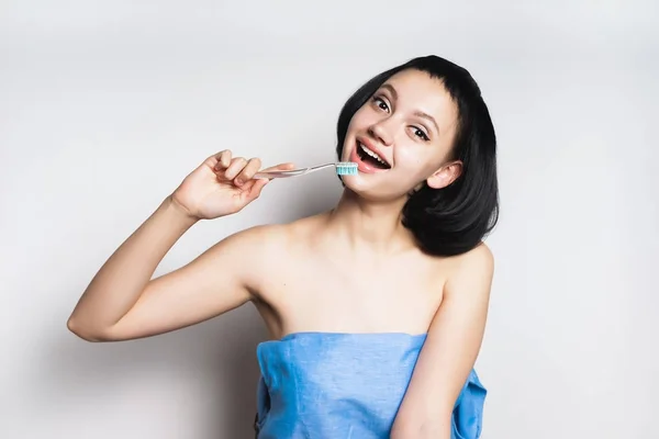 Happy νεαρό κορίτσι με τα μαύρα μαλλιά οδοντόβουρτσας κρατά στα χέρια της, χαμογελώντας — Φωτογραφία Αρχείου