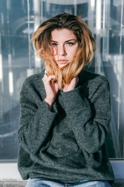 Kameraya bakarak bir cam duvar tarafından poz şık güzel sarışın