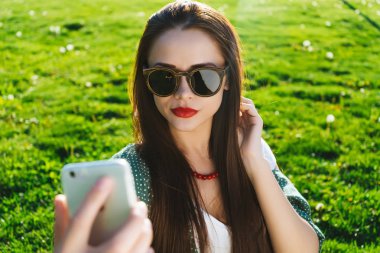 Kadının selfie dışında boşaltmak, yeşil çimenlerin üzerinde oturan yapması