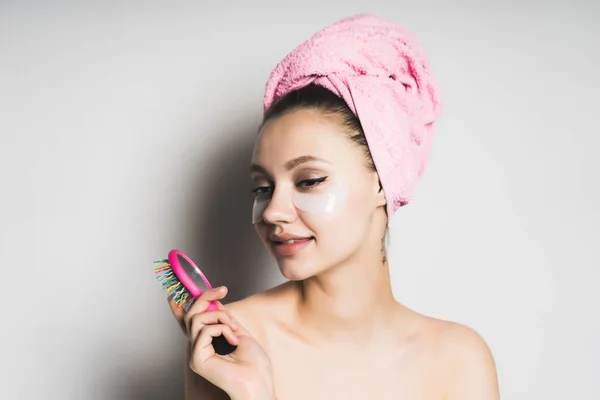 Chica con la piel limpia, con una toalla rosa en la cabeza sosteniendo un peine de pelo rosa en la mano — Foto de Stock