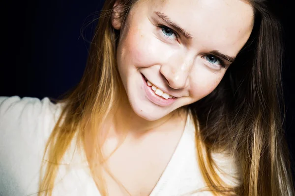 Ευτυχισμένος μακρυμάλλης κορίτσι μπλε-eyed σε λευκή μπλούζα χαμόγελο, βλέπουν τα φωτογραφικών μηχανών — Φωτογραφία Αρχείου