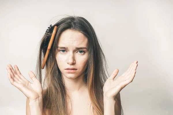 Uma jovem não pode pentear o cabelo, um pente de madeira é emaranhado em seu cabelo — Fotografia de Stock