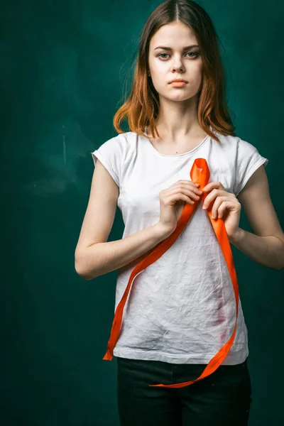 Jovem menina séria em uma camiseta branca segurando uma fita vermelha na forma de um símbolo — Fotografia de Stock