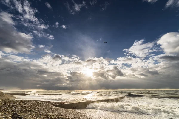El mar ruge en la playa de los guijarros, el cielo es nubes grises, el sol se asoma —  Fotos de Stock