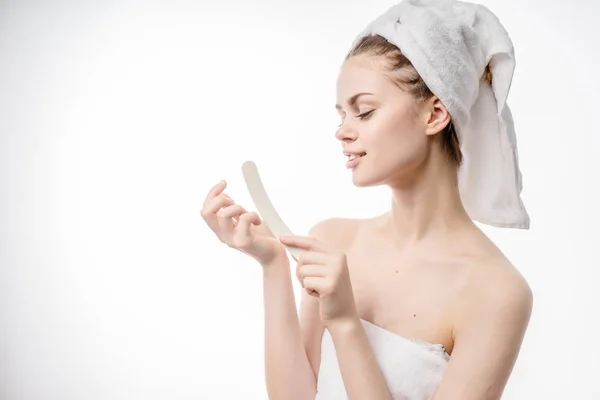 Mooi schattig meisje met een witte handdoek op haar hoofd zagen haar vingernagel nagelvijl — Stockfoto