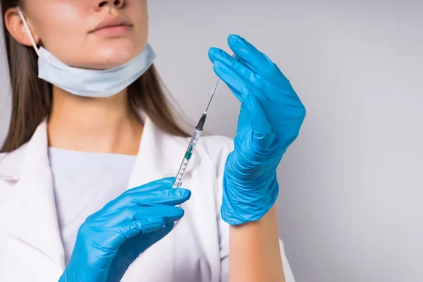 Niña doctor en bata médica blanca y guantes azules sostiene jeringa — Foto de Stock