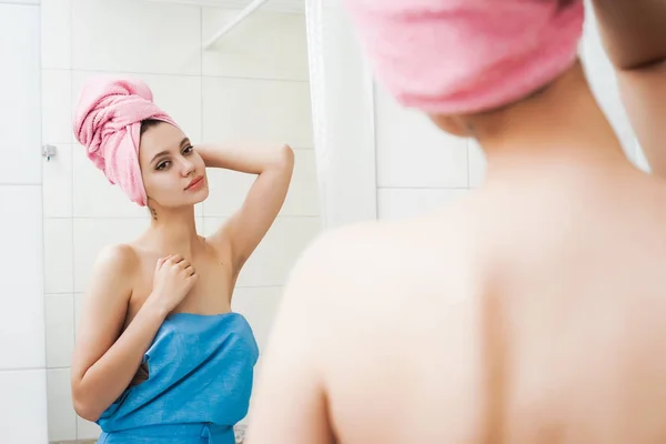 Söt flicka endast efter duschen med en rosa handduk på huvudet tittar på kameran — Stockfoto