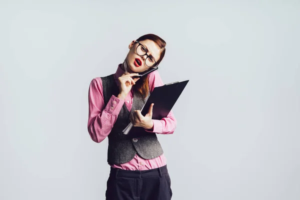 Mädchen im Arbeitsprozess. die Dame mit Brille telefoniert und hält die Ordner kaum in den Händen, isoliert — Stockfoto