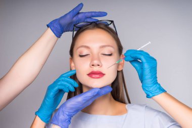 Gözlüklü genç bir kız yüz gençleştirme için iğne yapar