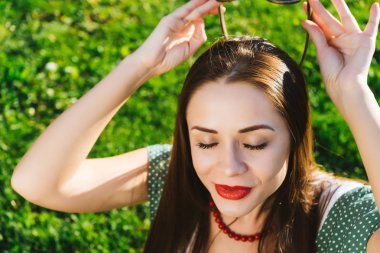 Neşeli mutlu kadın Koyu gözlüklü, yeşil çimenlerin üzerinde oturan