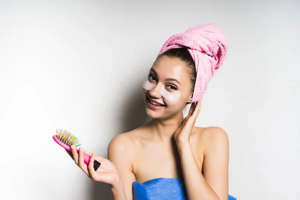 Όμορφη κοπέλα χαμογελαστή, φορώντας μια ροζ πετσέτα, κρατώντας μια βούρτσα στο χέρι — Φωτογραφία Αρχείου