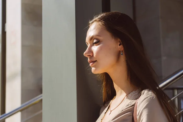 Attraente ragazza dai capelli lunghi in un abito beige gode del sole e del bel tempo — Foto Stock