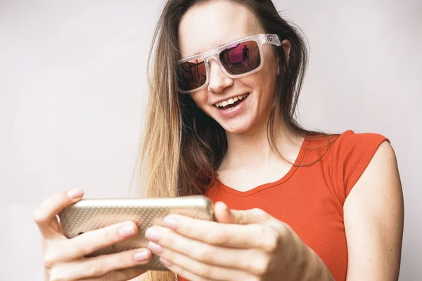 Divertente adolescente che fa selfie, femmina, in occhiali da sole, ride, su uno sfondo leggero — Foto Stock