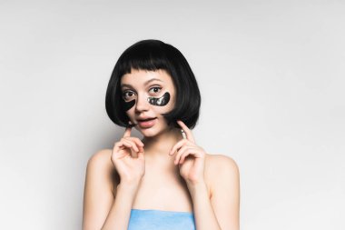 Siyah Silikon yamalar, gözleri altında siyah saçlı güzel çekici kız kameraya benziyor