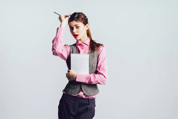 Stilvolles schönes Mädchen mit Brille, rotem Lippenstift, im rosa Hemd hält sie einen Ordner mit Dokumenten in der Hand, blickt in die Kamera — Stockfoto