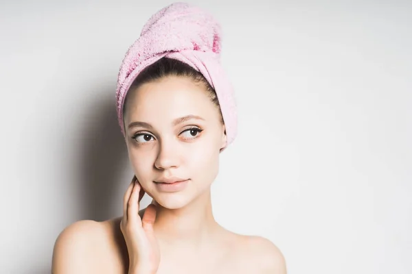 a young girl with a pink towel on her head thinks about how to look after her face