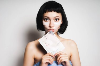 kısa siyah saçlı sevimli genç kız yüzünü sonra görünüyor, bir maske yüzü için tutar