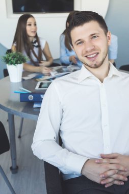 başarılı genç adam, memur, 2 genç kız birlikte çalışma arkasında bir beyaz gömlek gülümsüyor