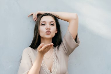 hafif bir duvarın ardında, poz çekici seksi kız bir hava öpücük gönderir