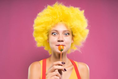 genç kız sarı palyaço peruk içinde chupa chups elinde tutan, o yemek istiyor