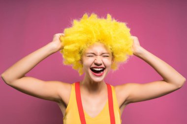 genç kız sarı palyaço peruk içinde güler, pembe bir arka plan