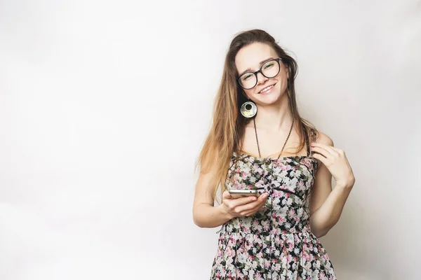 Feliz mujer positiva mensajes de texto en el teléfono, con gafas sobre un fondo blanco — Foto de Stock
