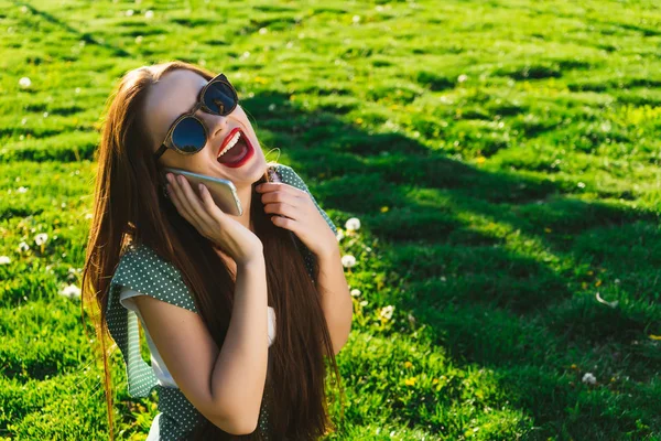 Счастливая улыбающаяся женщина получила хорошие новости, смеется, сидит на зеленой траве — стоковое фото