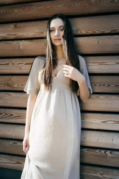 Modefrau auf der Straße, Holzhintergrund, blickt in die Kamera — Stockfoto