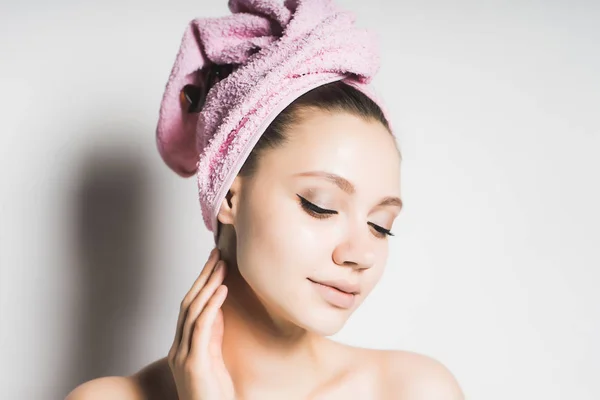 Ελκυστική κοπέλα με καθαρό δέρμα, με μια ροζ πετσέτα στο κεφάλι της, τα μάτια κλειστά, χαμογελώντας — Φωτογραφία Αρχείου