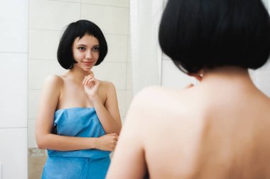 sevimli çekici kız siyah saçlı, mavi bir havlu ile görünüyor kendisi aynaya, gülümseyen