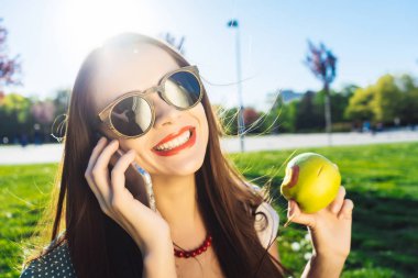 Güzel kadın gülümseme. Diş beyazlatma. Diş care.holding elleri ve telefonda konuşurken bir elma