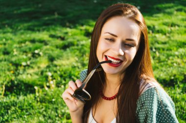 Gülümseyen kadın güneş gözlüğü, boşaltmak tutar. Gözlük ile çevresinde yeşil çimen