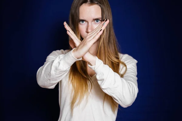 Langhaarige junge Frau in weißer Jacke zeigt mit den Händen ein Stoppschild — Stockfoto