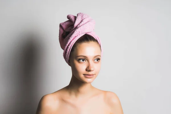 Vacker söt flicka med ren hud, med en rosa handduk på huvudet poserar, tittar bort — Stockfoto